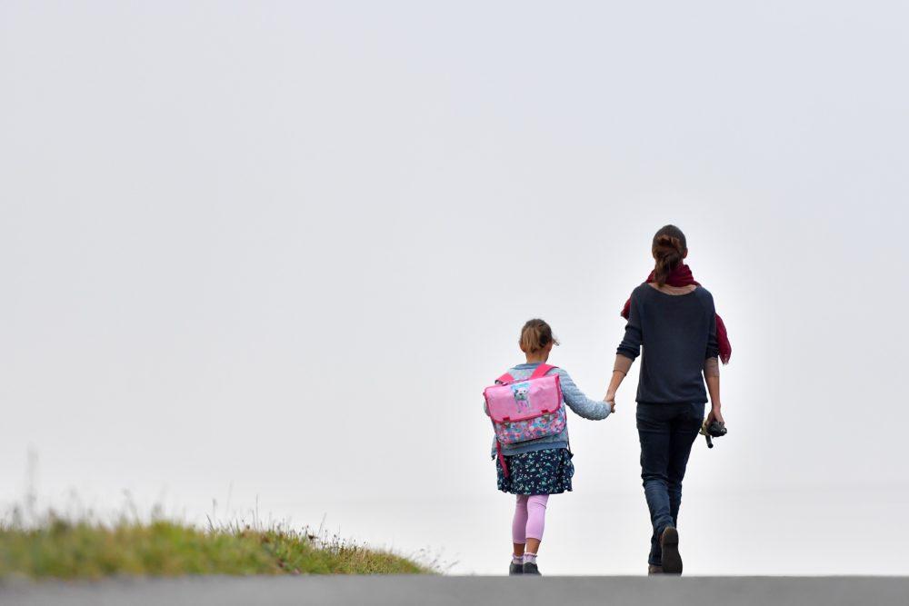 A girls walks to her primary school with her mother on the first day of the new school year in Vertou, western France, on September 4, 2017. / AFP PHOTO / LOIC VENANCE        (Photo credit should read LOIC VENANCE/AFP via Getty Images)