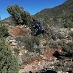Emergency crews work to free two people after a car crashes into a tree off I-15