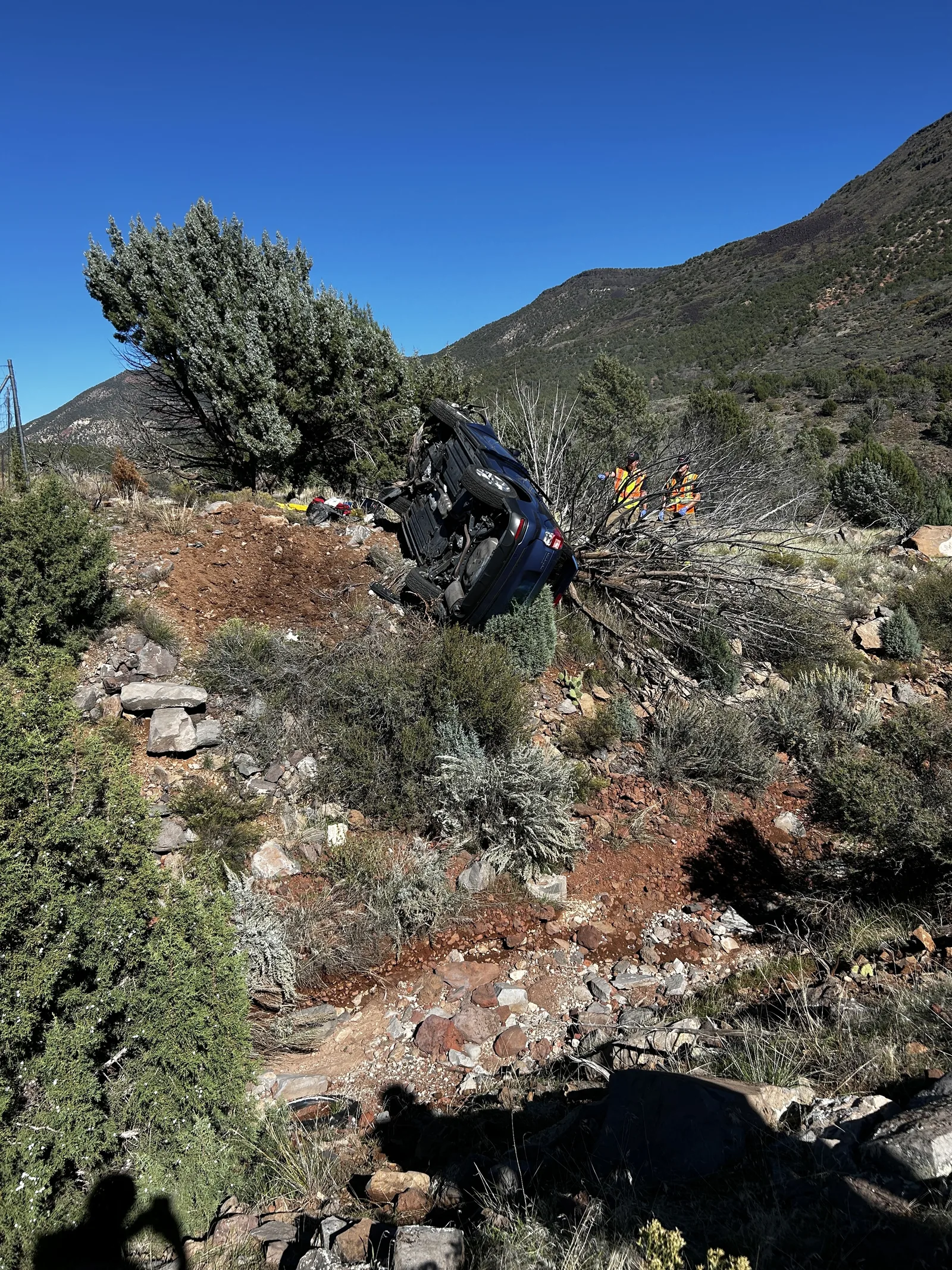 Emergency crews work to free two people after a car crashes into a tree off I-15