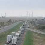 Emergency response crews at a closed Interstate 65 crash scene with traffic backed up nearby