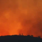 Dry hillside landscape in California with wildfire smoke and heat haze over distant mountains