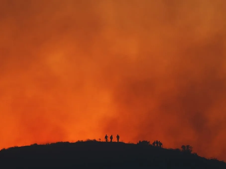 Dry hillside landscape in California with wildfire smoke and heat haze over distant mountains