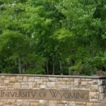 University of Wyoming campus sign with an inset of airport police arresting a woman
